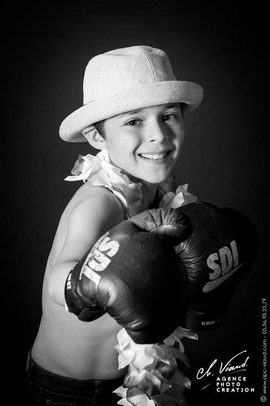 Portrait studio d'un garçon en noir et blanc avec un chapeau et des gants de boxe