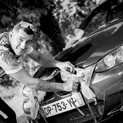 Reportage mariage, photo fun du marié qui décore sa voiture pour le mariage